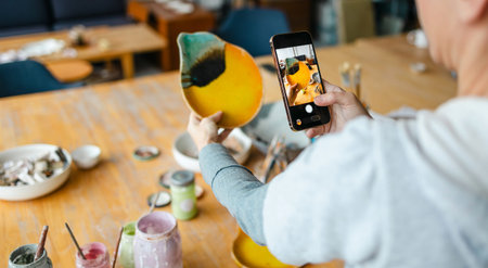 Cropped image of woman photographing with smartphone at table in cafe