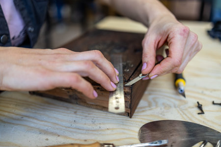 Close-up of female hands working with wood in a workshop.