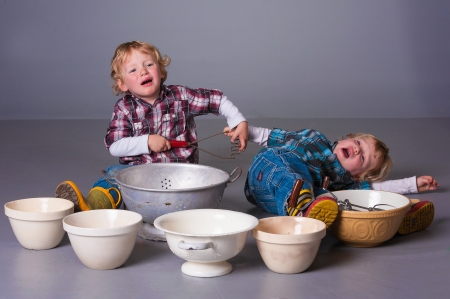 Twin boys bicker over cooking utensilsの写真素材