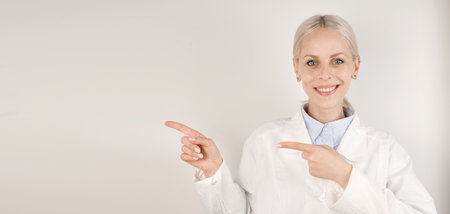 Young happy female doctor pointing at empty space.Medical banner with place for textの写真素材