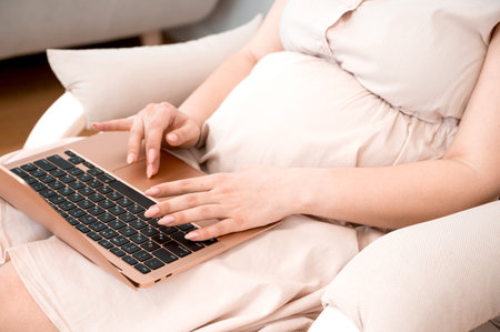 Pregnant woman uses laptop for work,online shopping,readin the blog or online appointment with a...