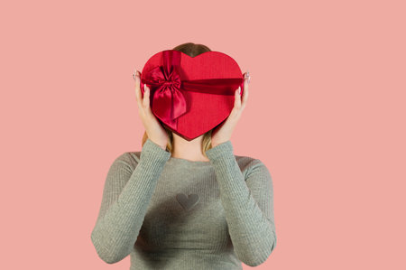 Studio portrait of a smiling female holding heart shaped gift box.Banner with place for textの写真素材
