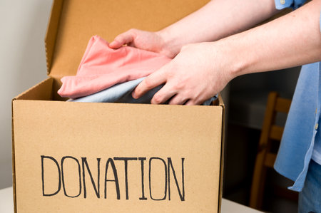 A volunteer packing clothes for donation in teh box. Giving and sharingの写真素材