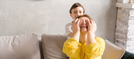 Son closing his mother eyes with his hands.Happy family.prepapring surpriseの写真素材