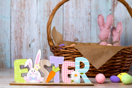 Easter wooden sign stads against easter basket with eggs and toy bannies.Happy easter banner