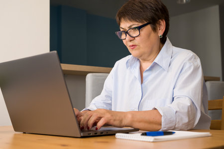 Serious elder woman woking on laptop at home. business woman. remote work conceptの写真素材