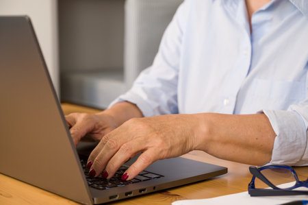 Side view on unrecognizable elder woman working on laptopの写真素材
