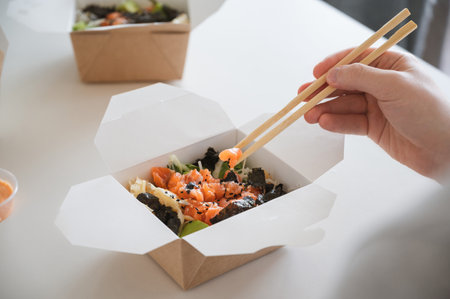 unrecognizable man eating poke bowl with salmon,seaweed,avocado etcの写真素材