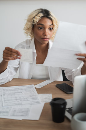 Shocked woamn looking at the bills and invoices for the mortgage,loan,utility payments and other expenses.の写真素材