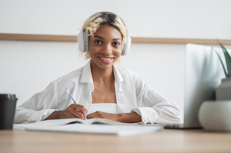 Smiling african american student girl sitting at the desk looking at the camera. E-learning, online education conceptの写真素材