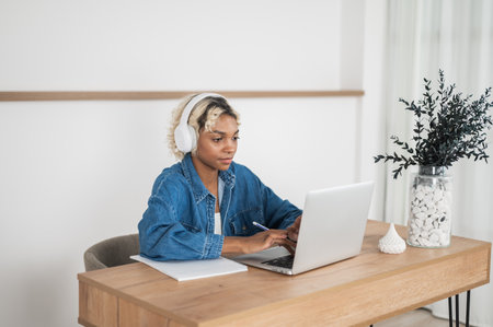 Freelancer working remotely from her home or college student studying at home.Girl with pen and notebook searching smth on laptopの写真素材