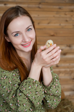 Easter concept. Vertical portrait of Young red head girl holding cute little chickenの写真素材