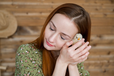 Easter concept. Young red haired girl holding cute little chickenの写真素材