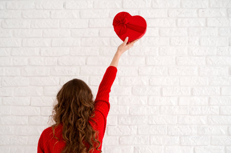 Copyspace banner with St Valentine's concept. Female in red sweater holding heart shaped gift boxの写真素材