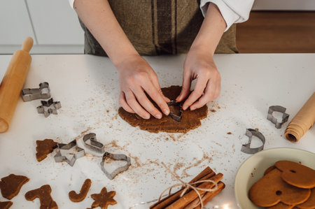 woman cutting out gingerbread cookies from the dough for christmas