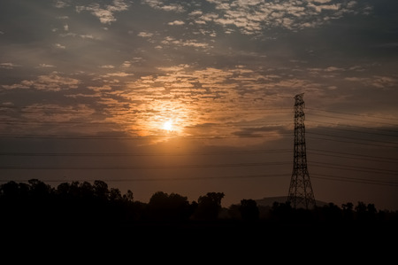 High voltage power transmission towers in sunset sky backgroundの写真素材