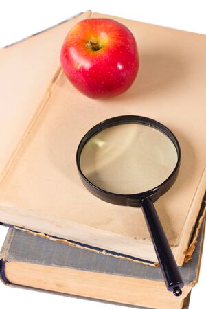  few age-old books, apple and magnifying glassの写真素材