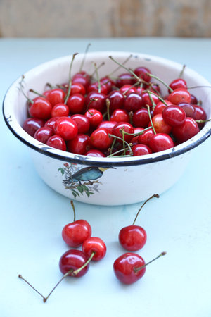 many ripe raw wet sweet cherry in dish on wooden background