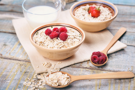 oat flakes with raspberry and strawberry in a bowl on textileの写真素材