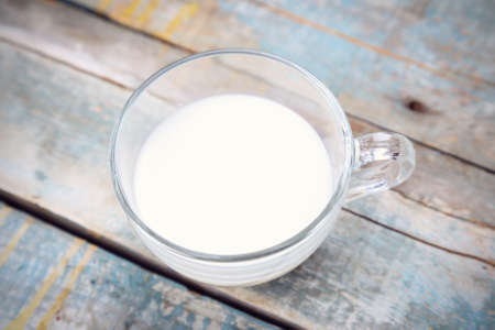 cup with fresh milk on blue wooden backgroundの写真素材