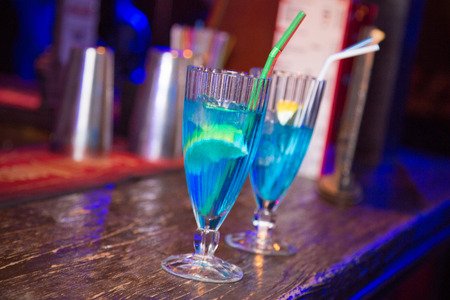 an alcoholic blue cocktail is in beautiful glass, on the barの写真素材