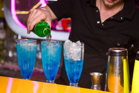 an alcoholic blue cocktail is in beautiful glass, on the barの写真素材