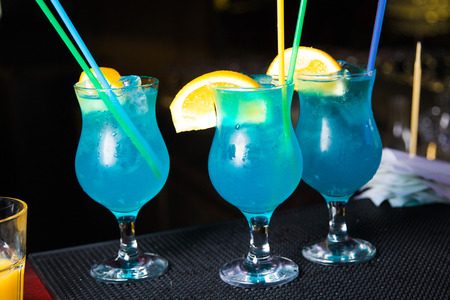 an alcoholic blue cocktail is in beautiful glass, on the barの写真素材