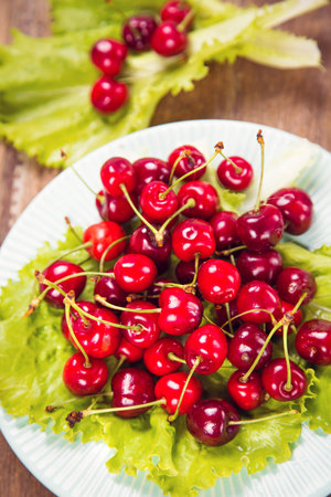 fresh ripe raw red sweet cherry on green lettuceの写真素材