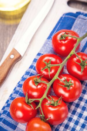 few fresh ripe tomatoes on a branch with olive oilの写真素材