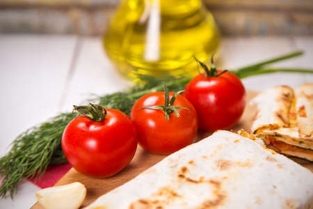 tortilla,tomatoes,dill,garlic and oil in bottle on wooden plate in studioの写真素材