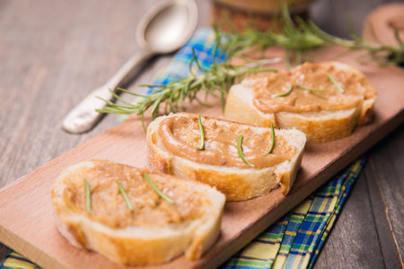 fresh bread with pork pate and rosemary on wooden plate