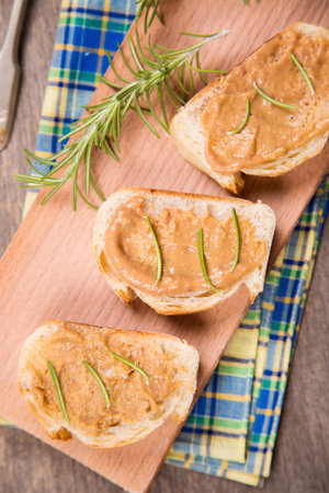 fresh bread with pork pate and rosemary on wooden plate