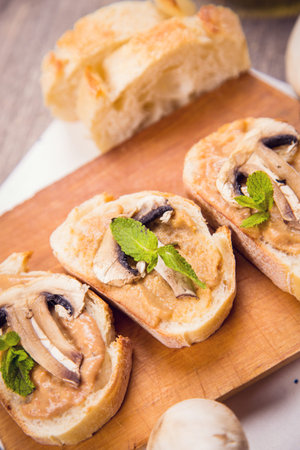 bread with pate,fried mushrooms and mint on wooden plateの写真素材