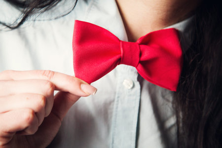 new red bow tie on adult woman indoorの写真素材