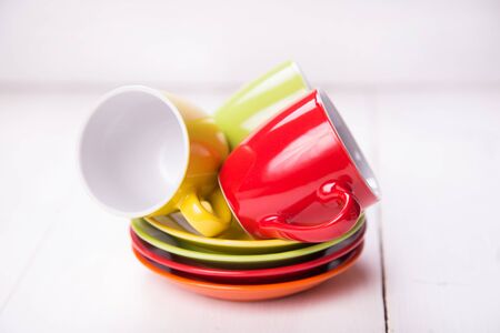 some colored empty cups on white wooden backgroundの写真素材