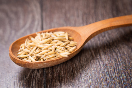 ripe dry oat is in a wooden spoon, in a studio