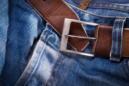 old leather belt on blue jeans textile in studio