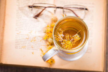tea on old book with yellow flowers in studioの写真素材