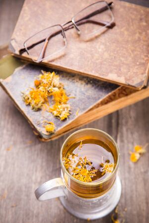 tea on old book with yellow flowers in studioの写真素材