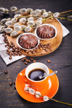 orange cup of coffee with chocolate cakes and willow flowersの写真素材