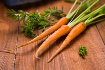 ripe fresh raw carrot with leaf on wooden background