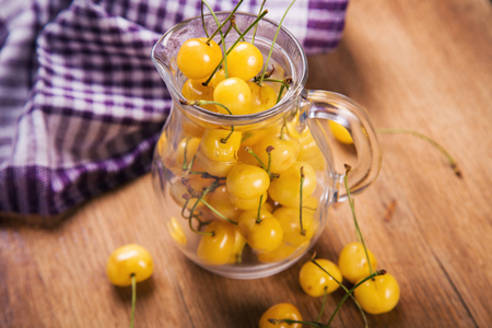 some ripe raw yellow sweet cherry in transparent jug in studioの写真素材