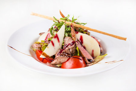 hot salad with meat and pear in dish isolated on white backgroundの写真素材