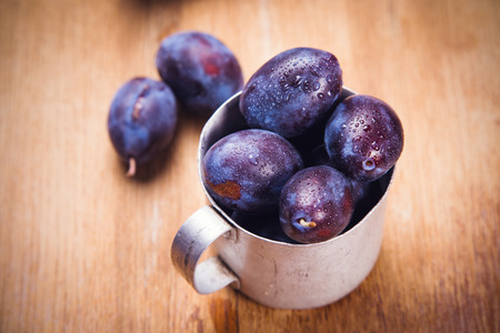 some blue raw ripe plums in old cup in studioの写真素材