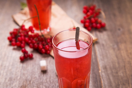 fresh hot viburnum tea in glass on wooden background