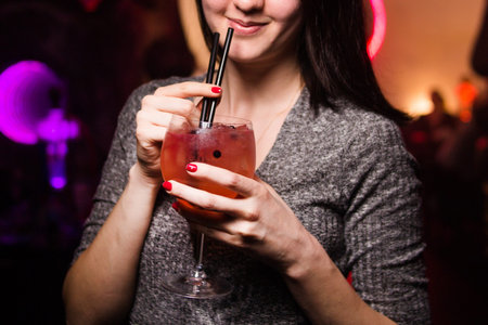 an alcoholic red cocktail is in beautiful glass,in hands
