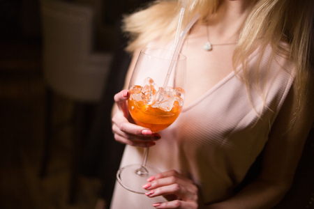 an alcoholic orange cocktail is in beautiful glass, in handの写真素材