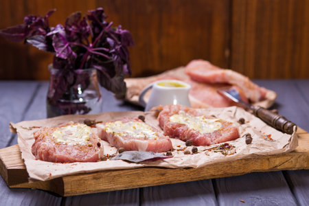some peace of raw meat with sauce and basil on wooden plateの写真素材