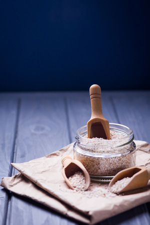 dry barley groats in glass container with wooden spoons in studioの写真素材