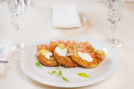 some potato pancakes with vegetables and herbs on white plate in restaurant